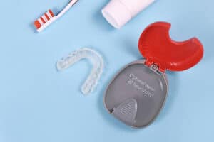 Clear aligner and case shown with toothbrush explaining how to clean Invisalign aligners