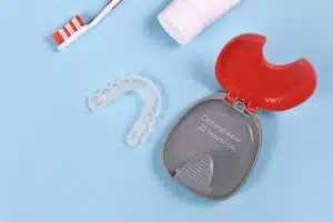 Clear aligner and case shown with toothbrush explaining how to clean Invisalign aligners